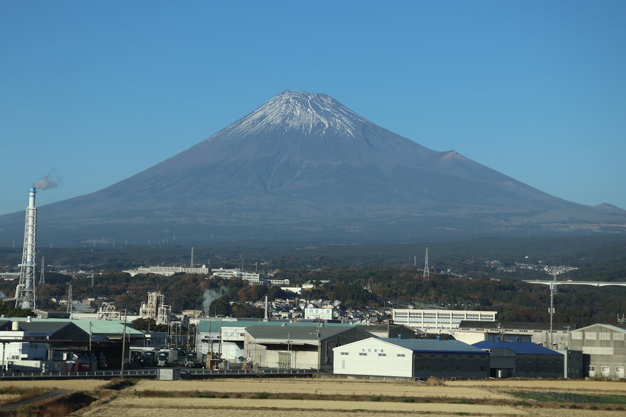 Mount Fuji towers over the industrial backdrop in Oyama, Shizuoka, Japan. Clear skies highlight this iconic peak.