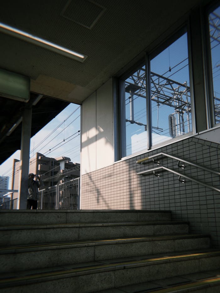 Serene view of a Japanese train station entry with city architecture visible.
