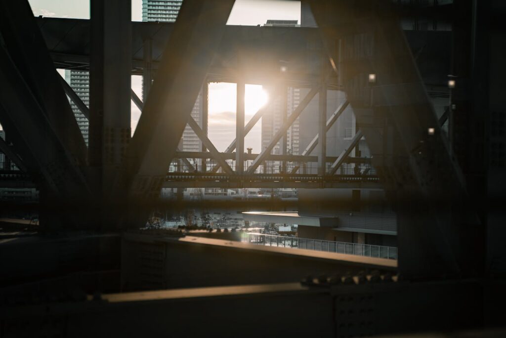Dramatic sunset through a steel bridge in Osaka, showcasing urban architecture and city vibes.